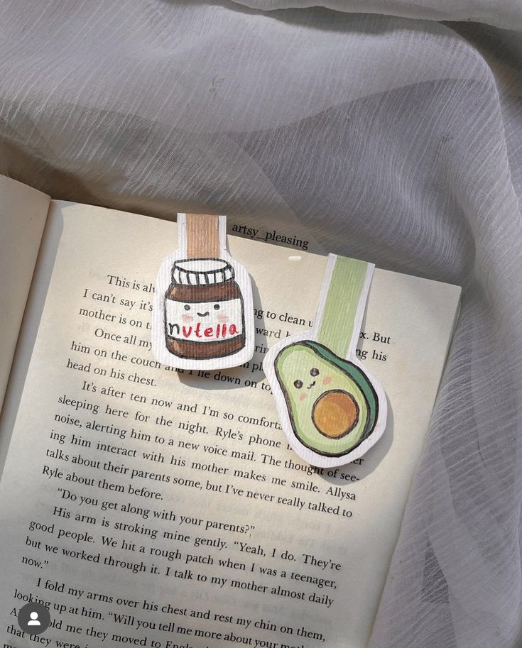 an open book with avocado and peanut butter on it sitting on a bed