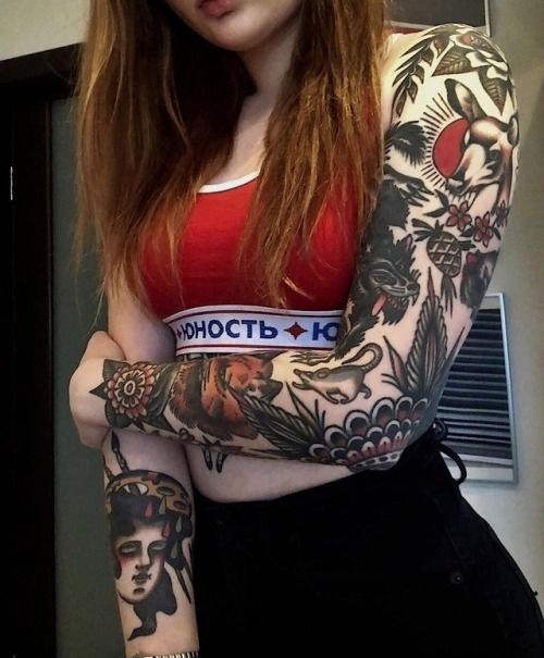 a woman with red hair and tattoos on her arm posing for a photo in front of a mirror