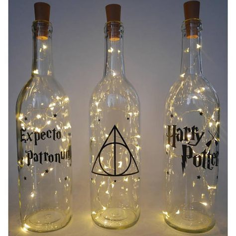 three harry potter bottles with fairy lights on the bottom and one in the middle, both empty