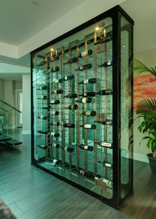 a large display case filled with lots of bottles and wine glasses on top of wooden flooring