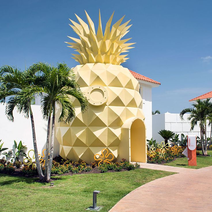 a large yellow pineapple shaped building sitting in the middle of a lush green park