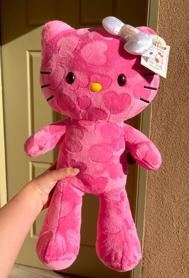 a pink hello kitty stuffed animal with a bow on its head