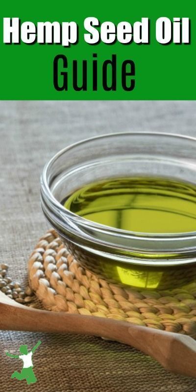 a bottle of hemp seed oil sitting on top of a table next to a wooden spoon