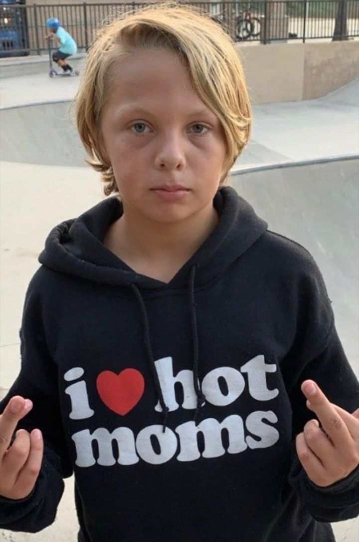 a young boy wearing a black hoodie with i love hot moms on it