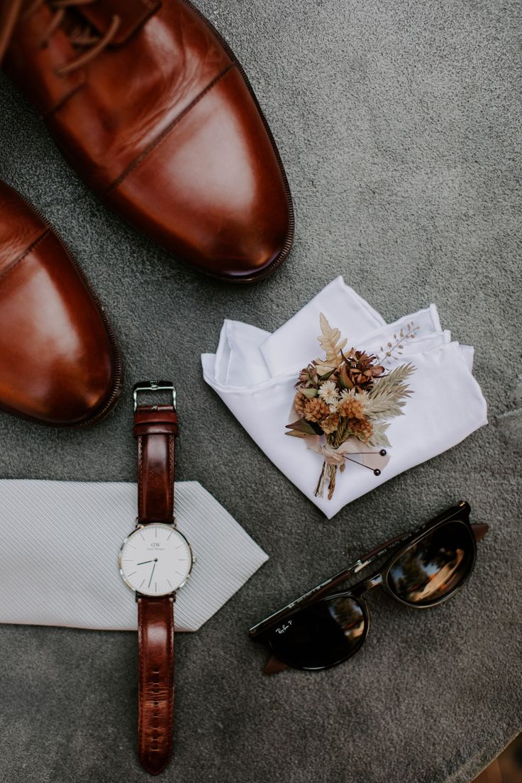 an assortment of men's clothing and accessories laid out on the ground next to their shoes