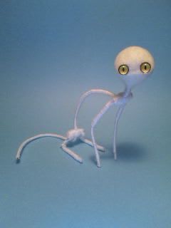 a small white toy with big eyes on a blue background