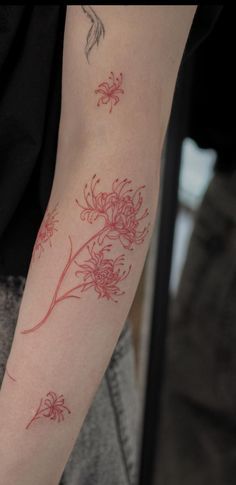 a woman's arm with red ink on it and flowers in the middle of her arm