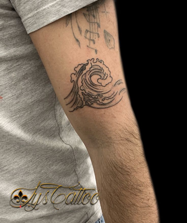 a man with a wave tattoo on his arm