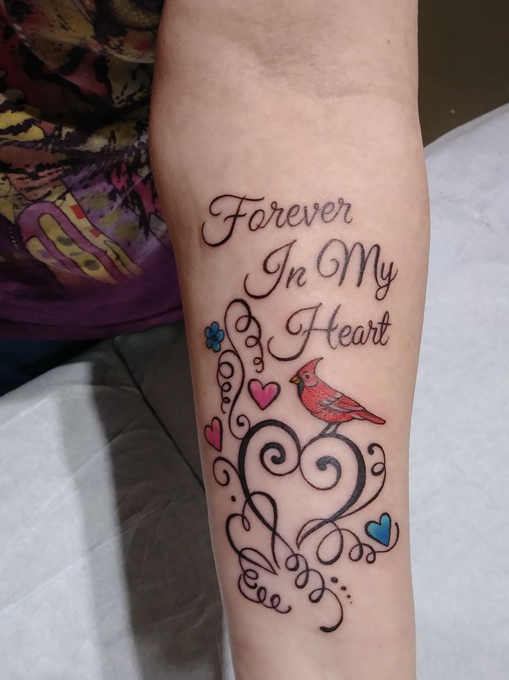 a woman with a tattoo on her arm that says forever in my heart and a bird