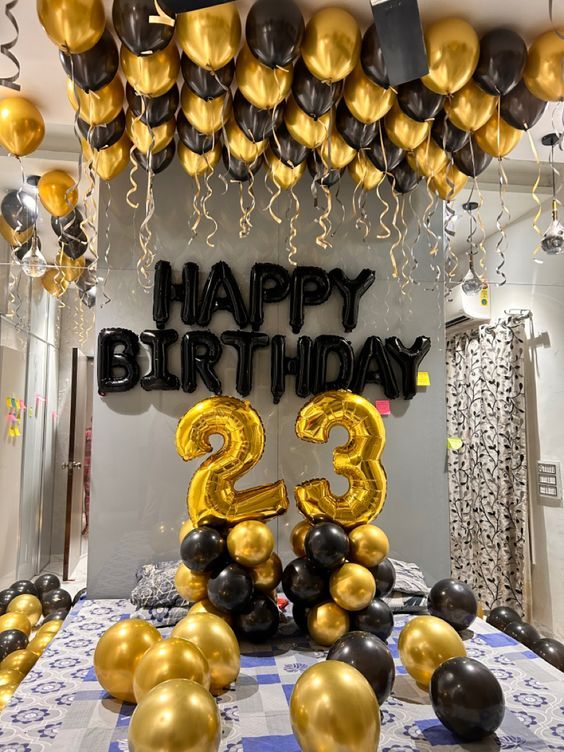 a table topped with balloons and black and gold decorations