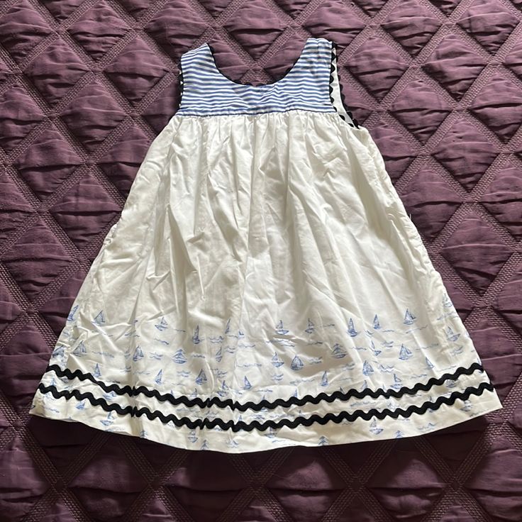 White Cotton Sleeveless Dress With Navy Ribbon Detail. Navy Anchor Buttons Up Back. White Summer Twirl Dress For Playtime, White Twirl Dress For Summer Playtime, Playful Sleeveless Playwear Dress, Playful Sleeveless Dress For Playwear, Sleeveless Playful Dress For Playwear, White Summer Sundress For Playwear, White Sundress For Summer Playwear, Sleeveless Sundress For Dress-up Occasion, White Sleeveless Sundress For Dress-up