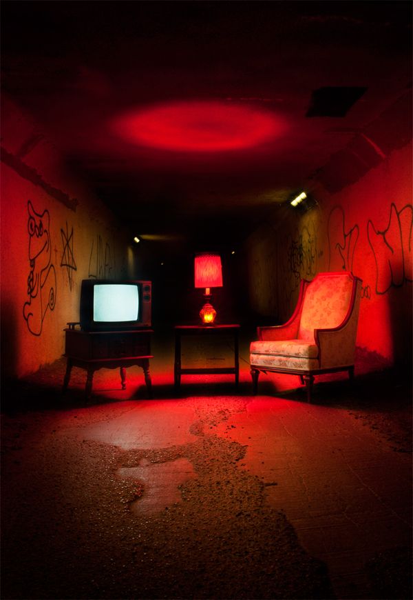 two chairs and a television in a dark room with graffiti on the walls, one chair has a red light