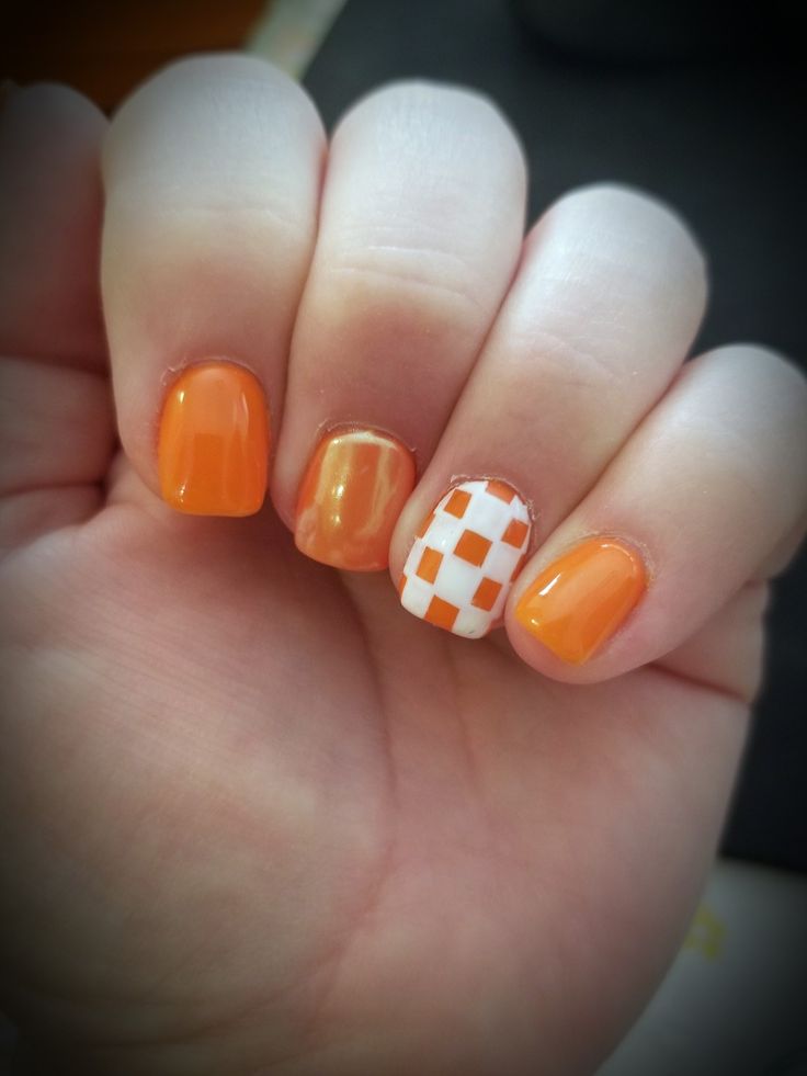 an orange and white checkered manicure on someone's hand