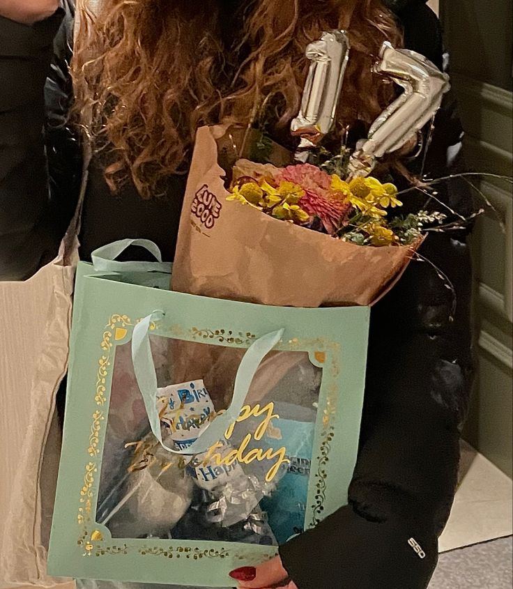 a woman is holding a bag with flowers in it and an i love you card