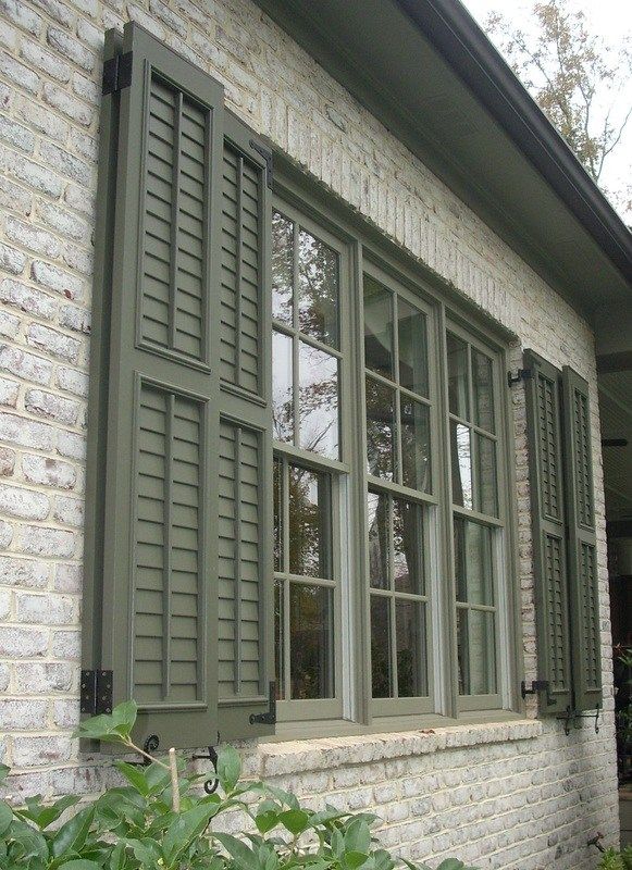 a brick house with green shutters and windows