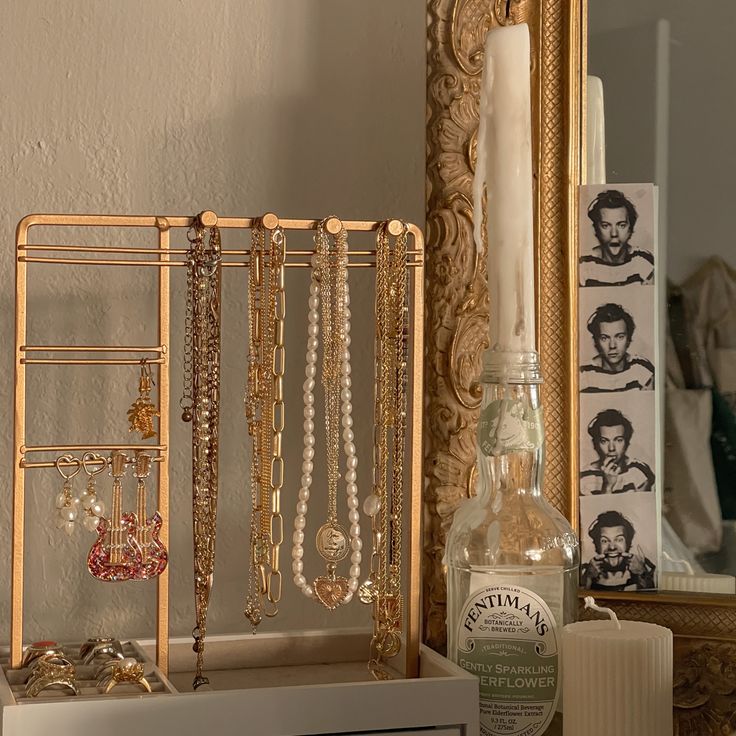 there are many necklaces on the shelf next to a candle and a glass bottle