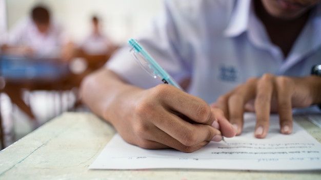 a man sitting at a table with a pen in his hand and writing on paper