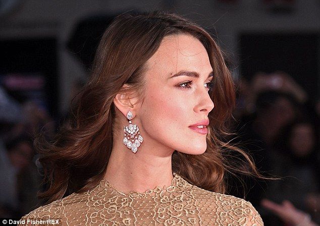 a woman with brown hair and earrings on her head looking off into the distance while standing in front of a crowd