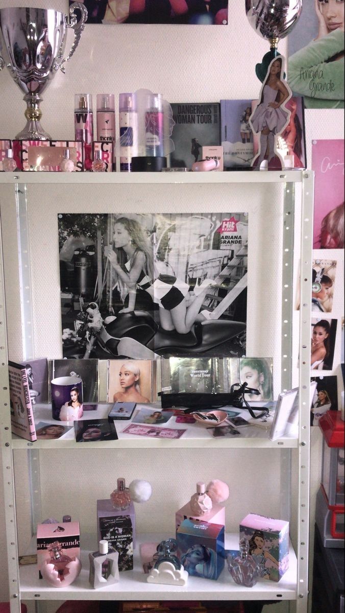 a white shelf filled with lots of items next to a wall covered in pictures and photos