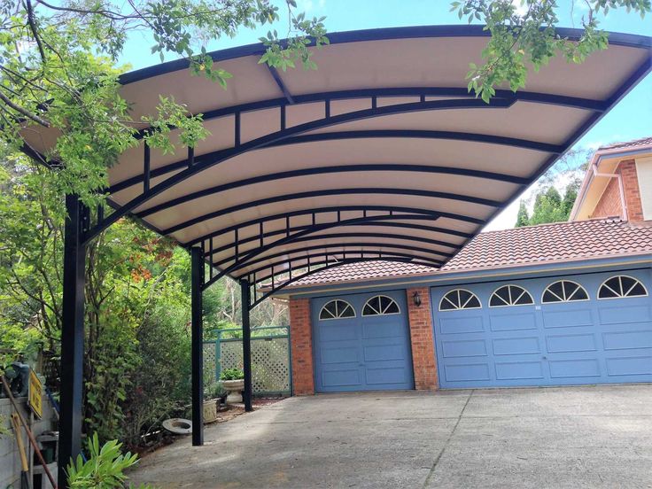 an attached carport in front of a house with blue garage doors and brick walls