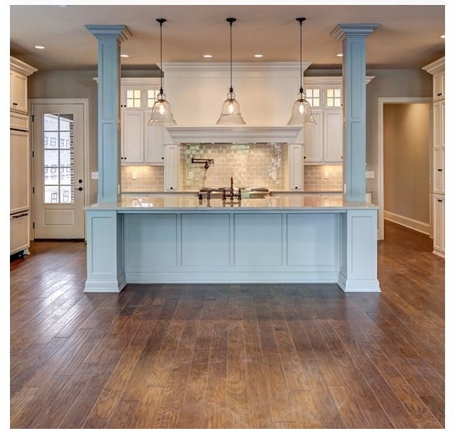 a large kitchen with an island in the middle and two pendant lights hanging from the ceiling