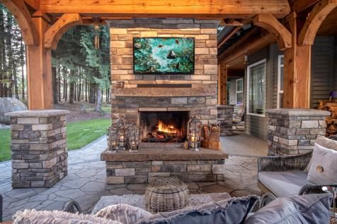 an outdoor living area with stone fireplace and seating