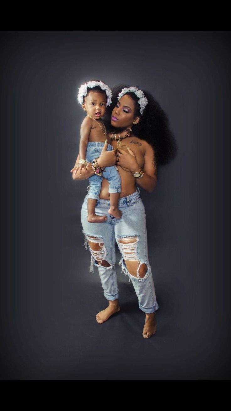 a woman holding a baby in her arms and posing for the camera with an afro hairstyle