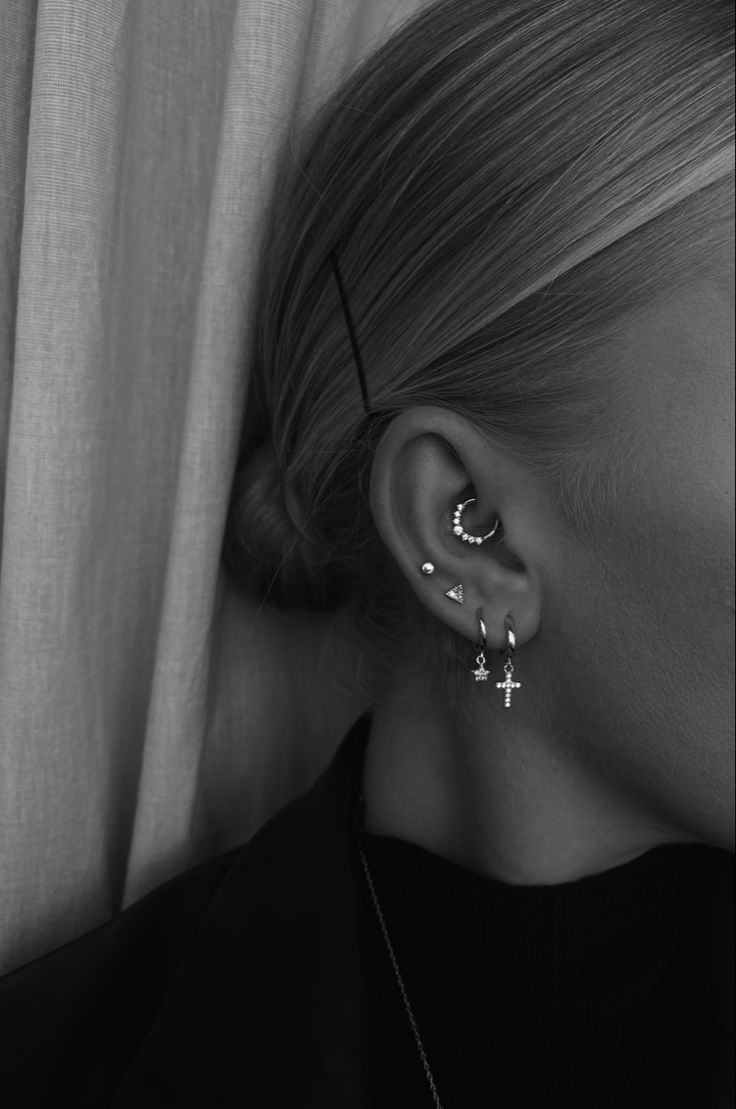 a woman wearing ear piercings with cross on it