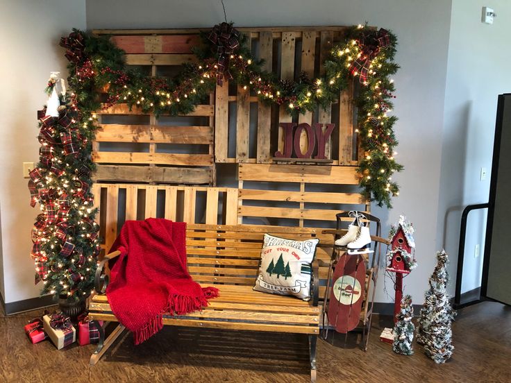 a wooden bench sitting in front of a wall covered with christmas decorations and lights on top of it