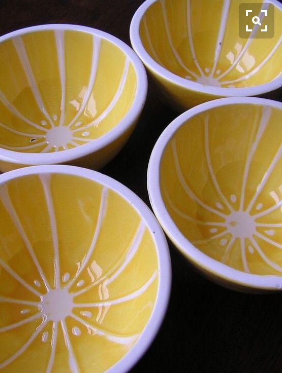 four yellow bowls sitting on top of a wooden table with white lines painted on them