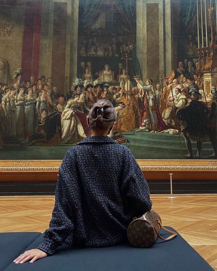 a woman sitting on a mat in front of a painting