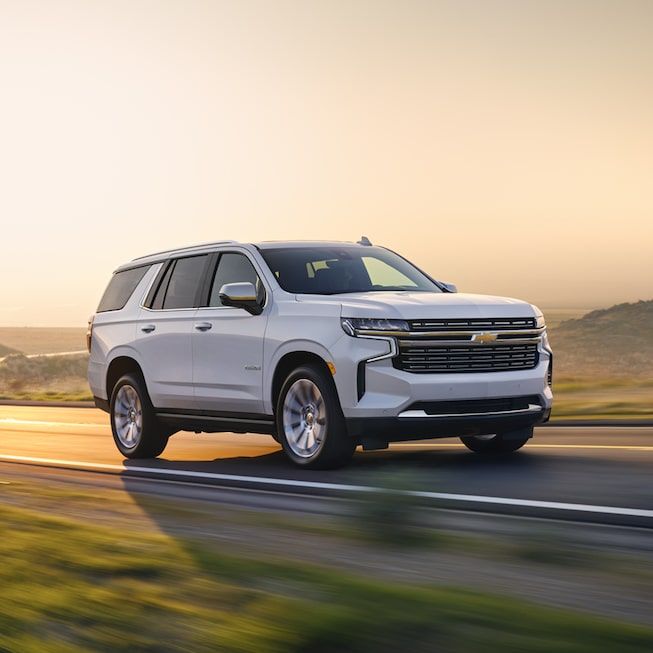 a white chevy suburban is driving down the road