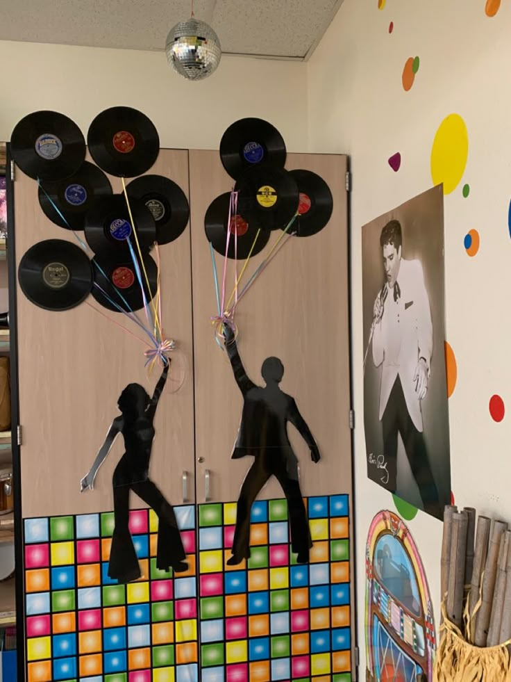 two black figures holding up record records in front of a wall with disco balls on it