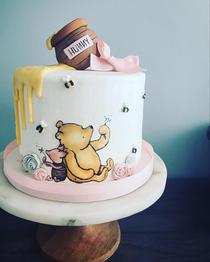 a winnie the pooh birthday cake with honey dripping on top and fondant decorations