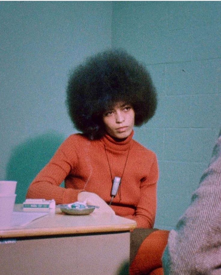 a woman with an afro sitting at a table