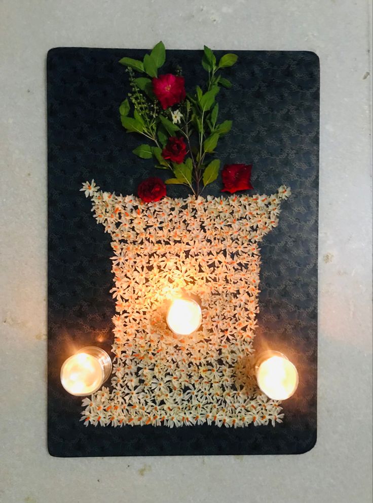 a candle holder with roses and candles in it on a table next to a wall