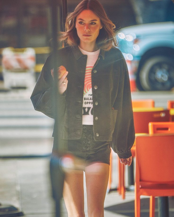 a woman in short shorts and boots is walking down the street with an umbrella over her head