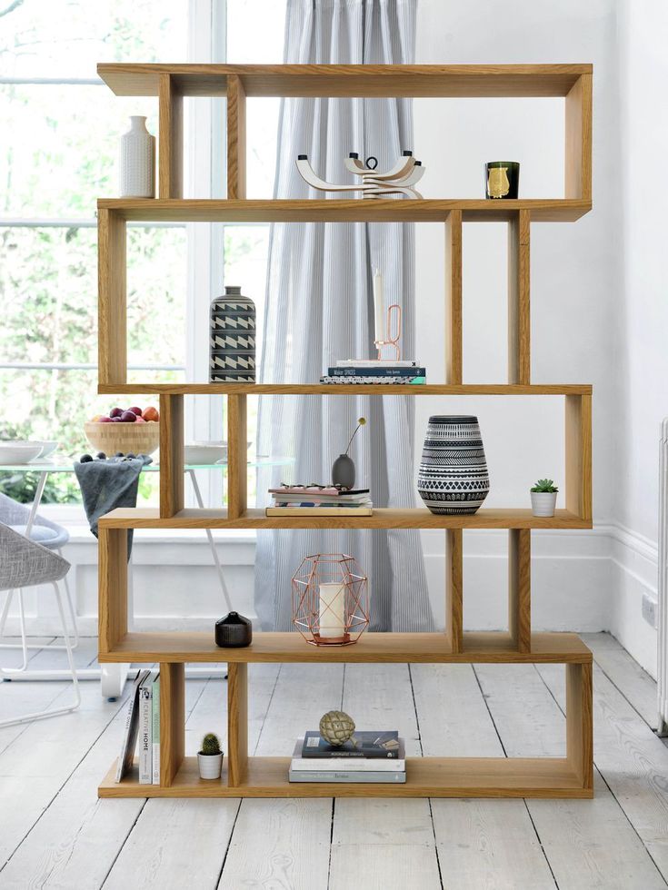 a bookshelf in the corner of a room with white walls and wooden floors