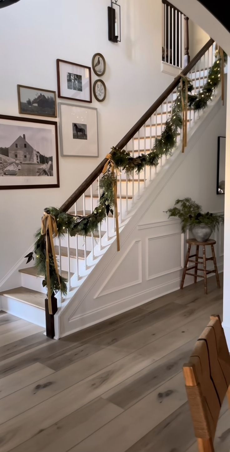 the stairs are decorated with christmas garlands and pine cones for holiday decor, along with pictures on the wall