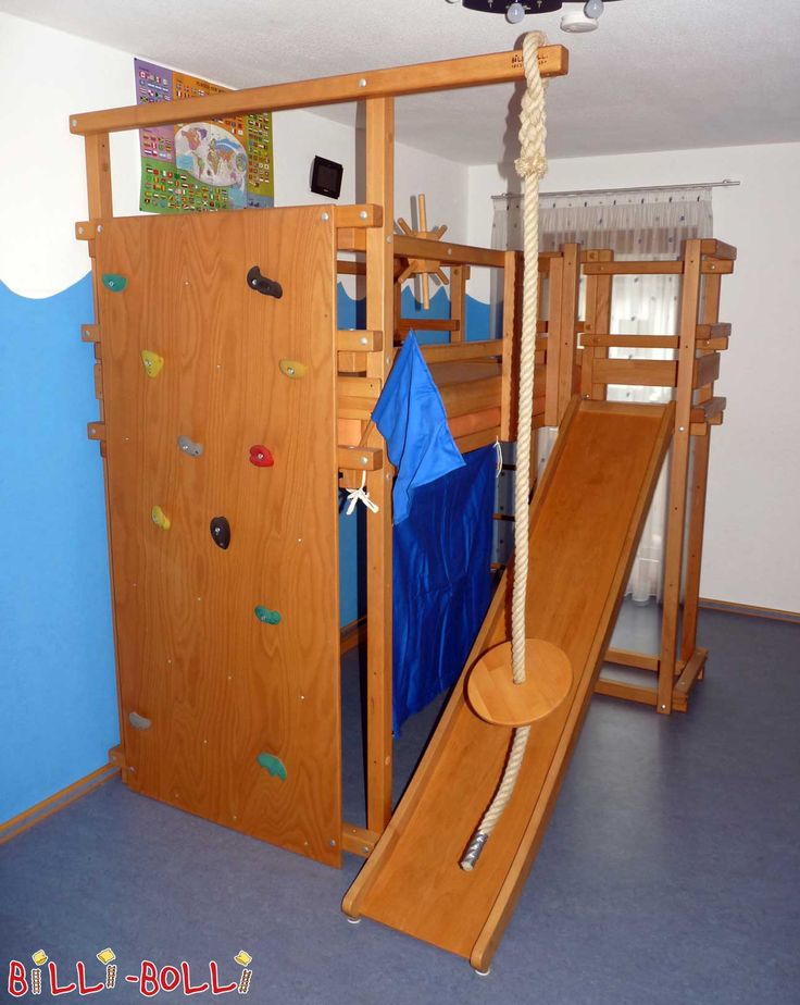 a child's play area with slide and climbing wall in the corner, next to a blue wall