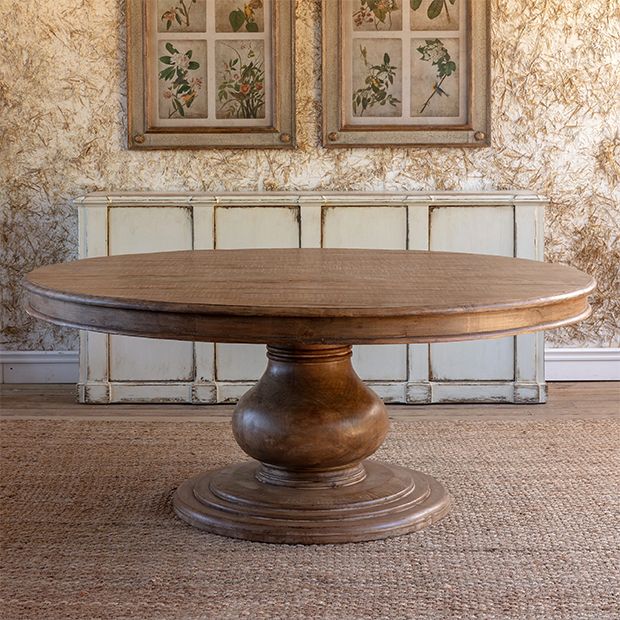 a round wooden table sitting on top of a carpeted floor next to two framed pictures