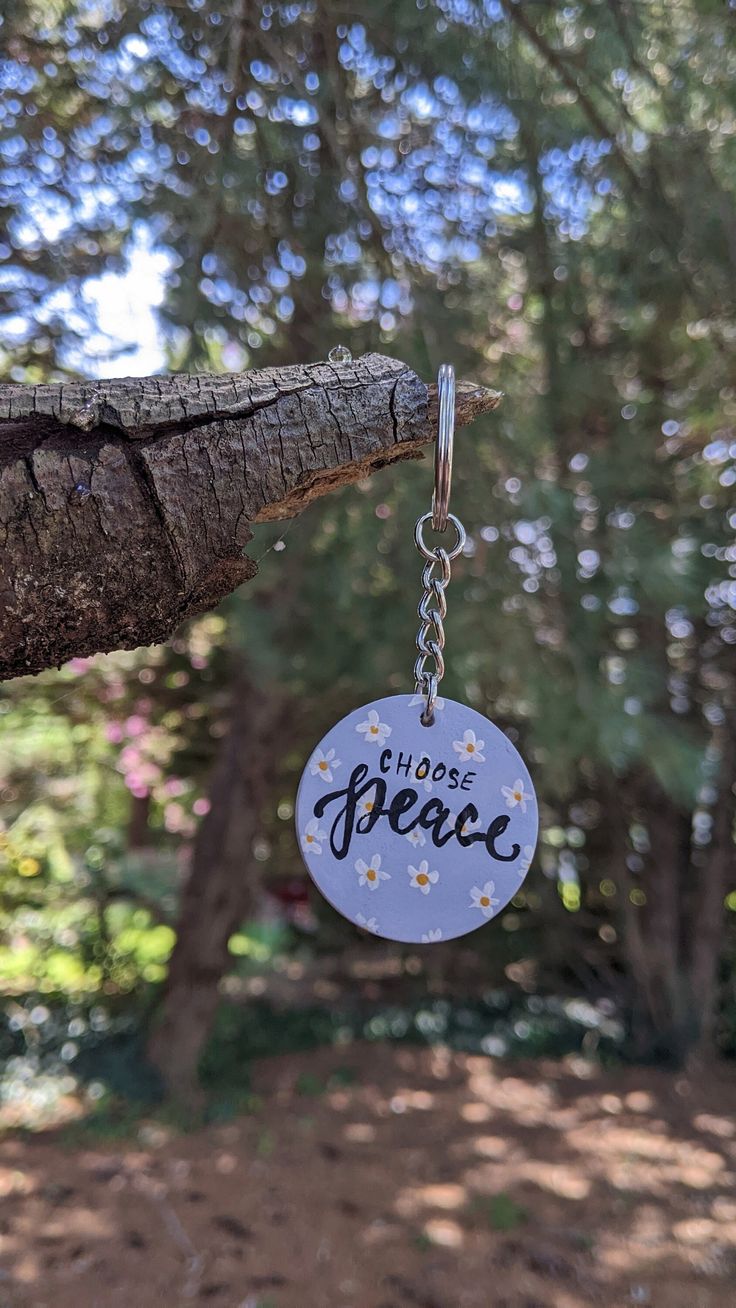 a keychain hanging from a tree branch with the word peace written on it