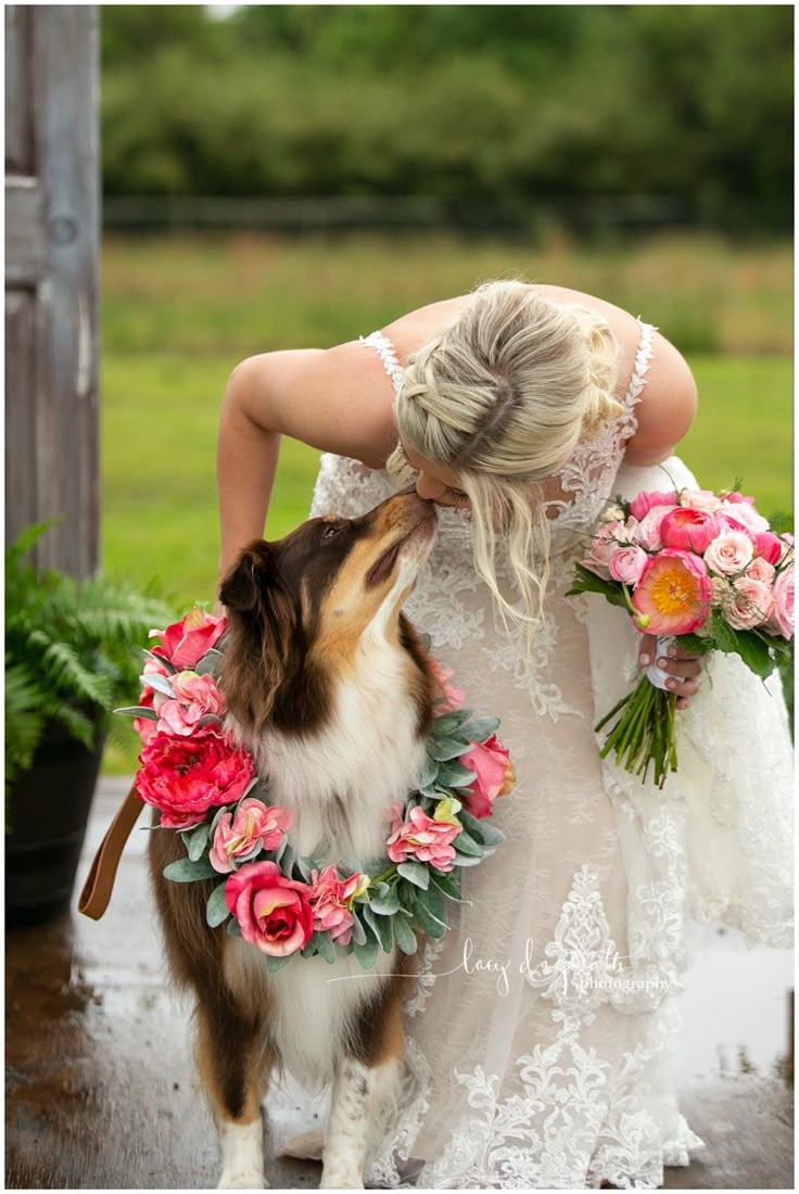 a woman in white dress kissing a dog with flowers around it's neck and head