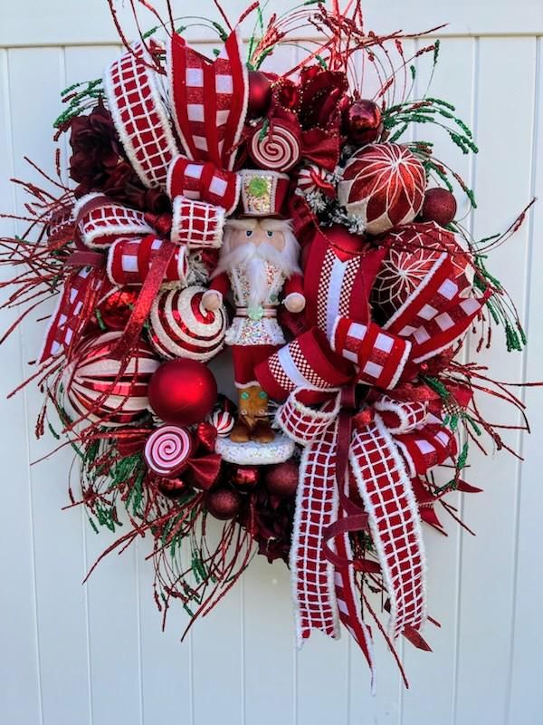 a christmas wreath hanging on the side of a door with candy canes and ornaments