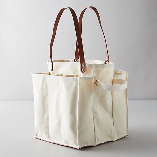 two canvas totes with leather handles on each side, one is white and the other is brown