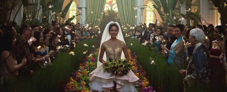 a woman in a wedding dress is walking down the aisle with flowers all around her