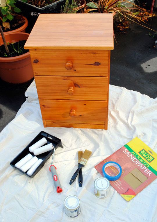 a wooden dresser sitting on top of a white sheet next to paint and other items