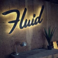 a sign that says fluid on the side of a wall next to a potted plant