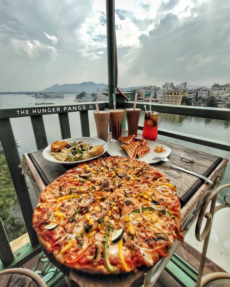 a large pizza sitting on top of a wooden table next to two plates of food