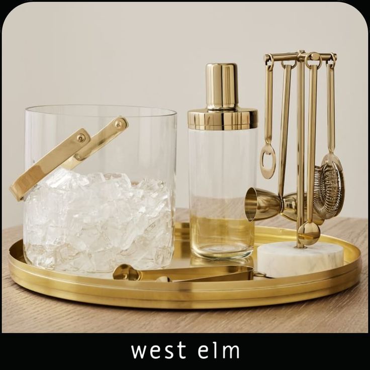 an assortment of glass and brass items on a tray with the words west elm written below it